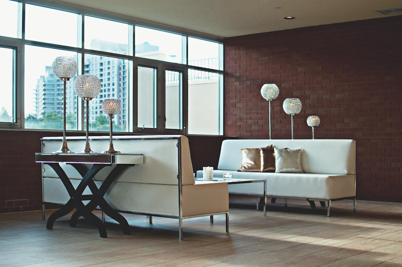 Bright lounge with white sofas, cushions and crystal floor lamps in front of large windows overlooking high-rise buildings